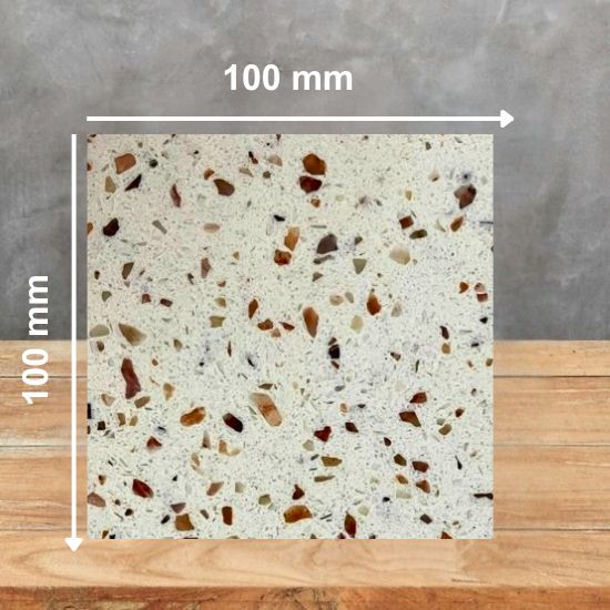 100 mm square sample of Venezia quartz in cream with multicolored specks, placed on a wooden surface against a grey background