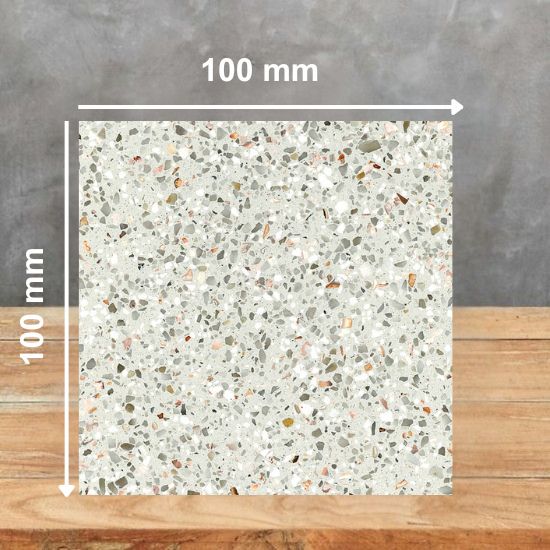 100 mm square sample tile of Quartzforms Terrazzo Casanova quartz in cream base with multicoloured grey beige pink copper specks, displayed on wooden surface