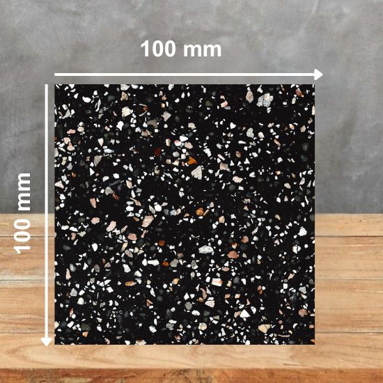 t100 mm square sample of Quartzforms Terrazzo Doge quartz in deep black with white pink and copper specks, displayed on wooden surface against grey background