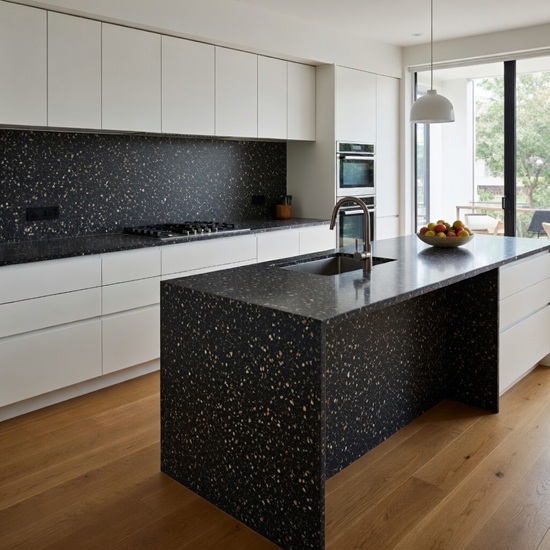 Quartzforms Terrazzo Doge quartz kitchen island and backsplash in deep black with white pink and copper specks, featuring sink, fruit bowl, white handleless cabinets and large windows in a bright open-plan kitchen