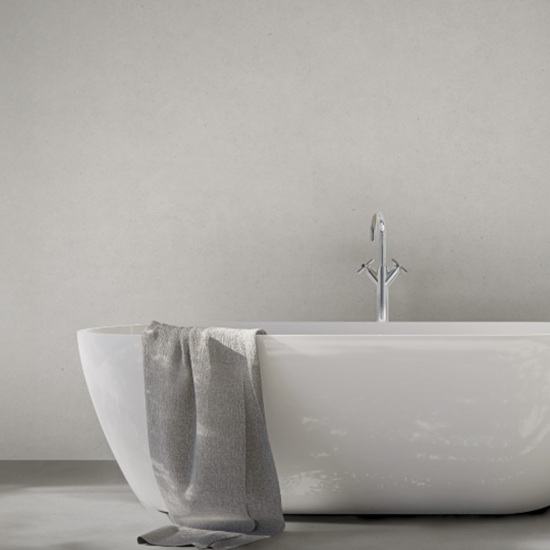 Techlam Limestone wall in soft light grey with natural limestone texture behind a modern freestanding white bathtub with chrome faucet and grey towel