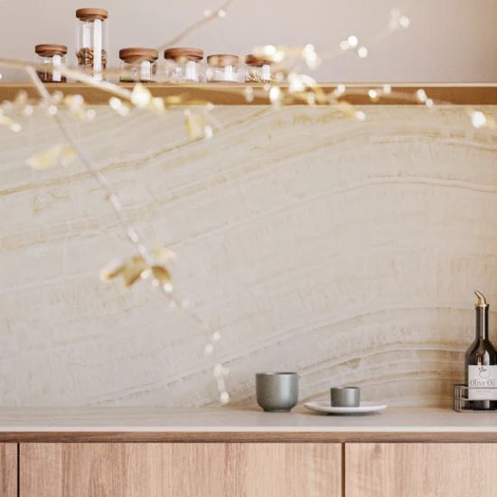 Close-up of Caesarstone Onyxa quartz splashback in a minimalist kitchen with floating wooden shelf, decorative branch and neutral ceramic accessories.